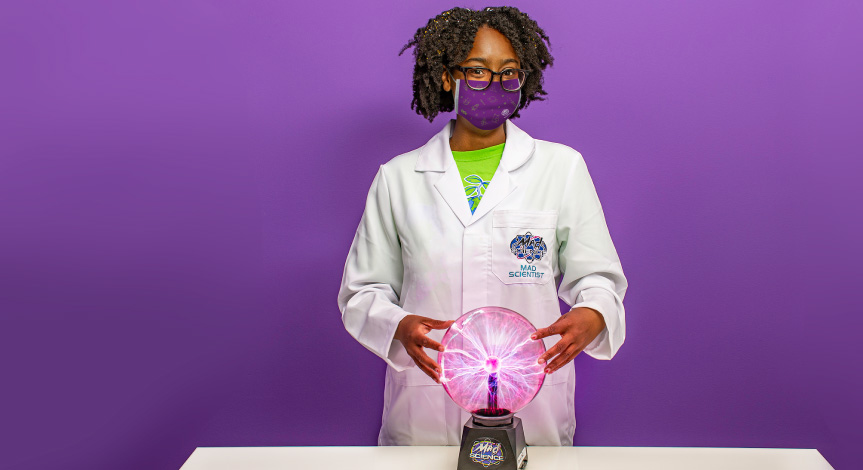 A mad Science instructor in a white mad science lab coat wearing a mad science mask touching a plasma ball